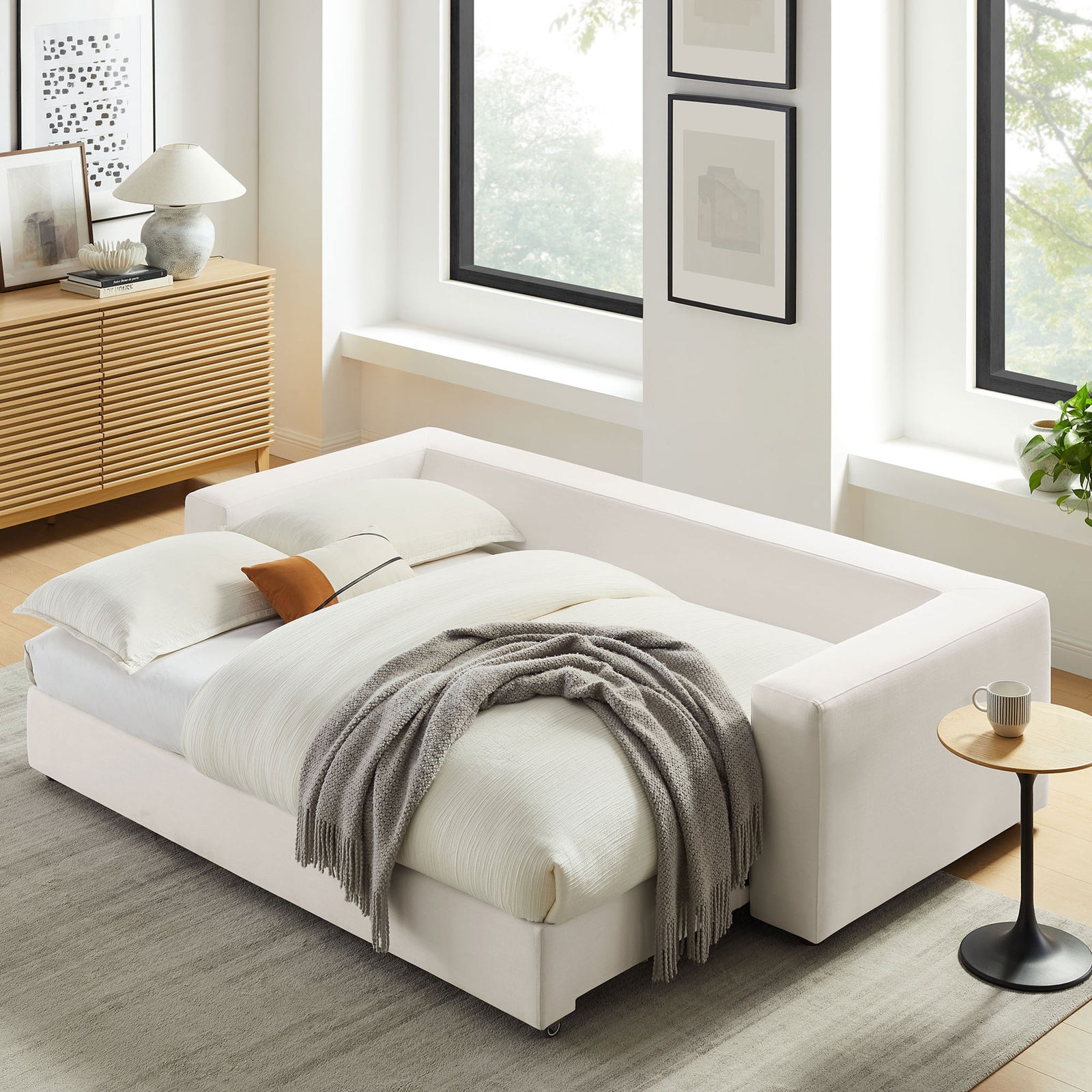 Sleeper sofa fully made as a cozy guest bed with layered bedding, throw blanket, and pillow || EEI-7080-PUW || front_angle_converted_room