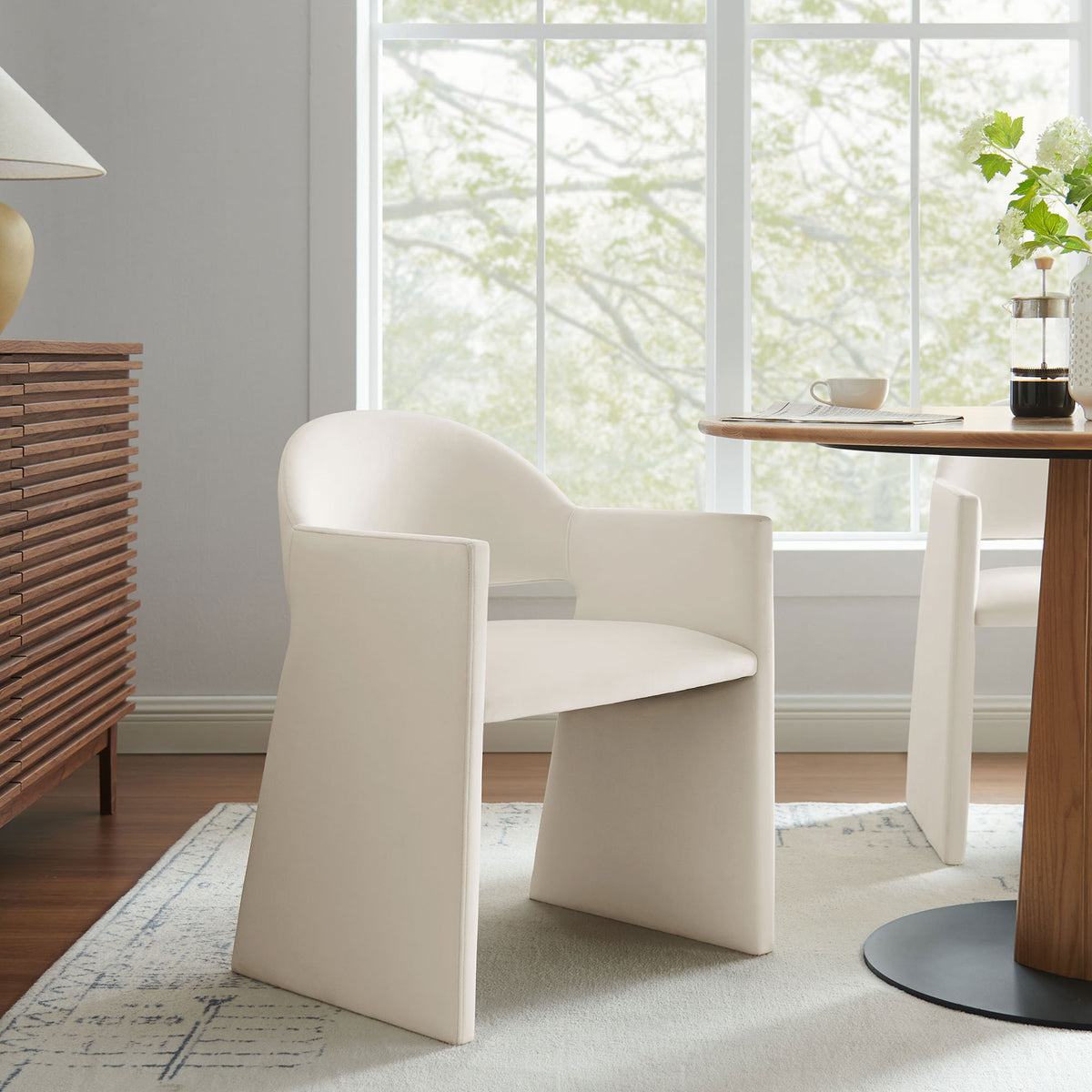 Talia alabaster velvet dining armchair styled in a bright dining room with wood table and credenza || EEI-7081-ALA || front_angle_room