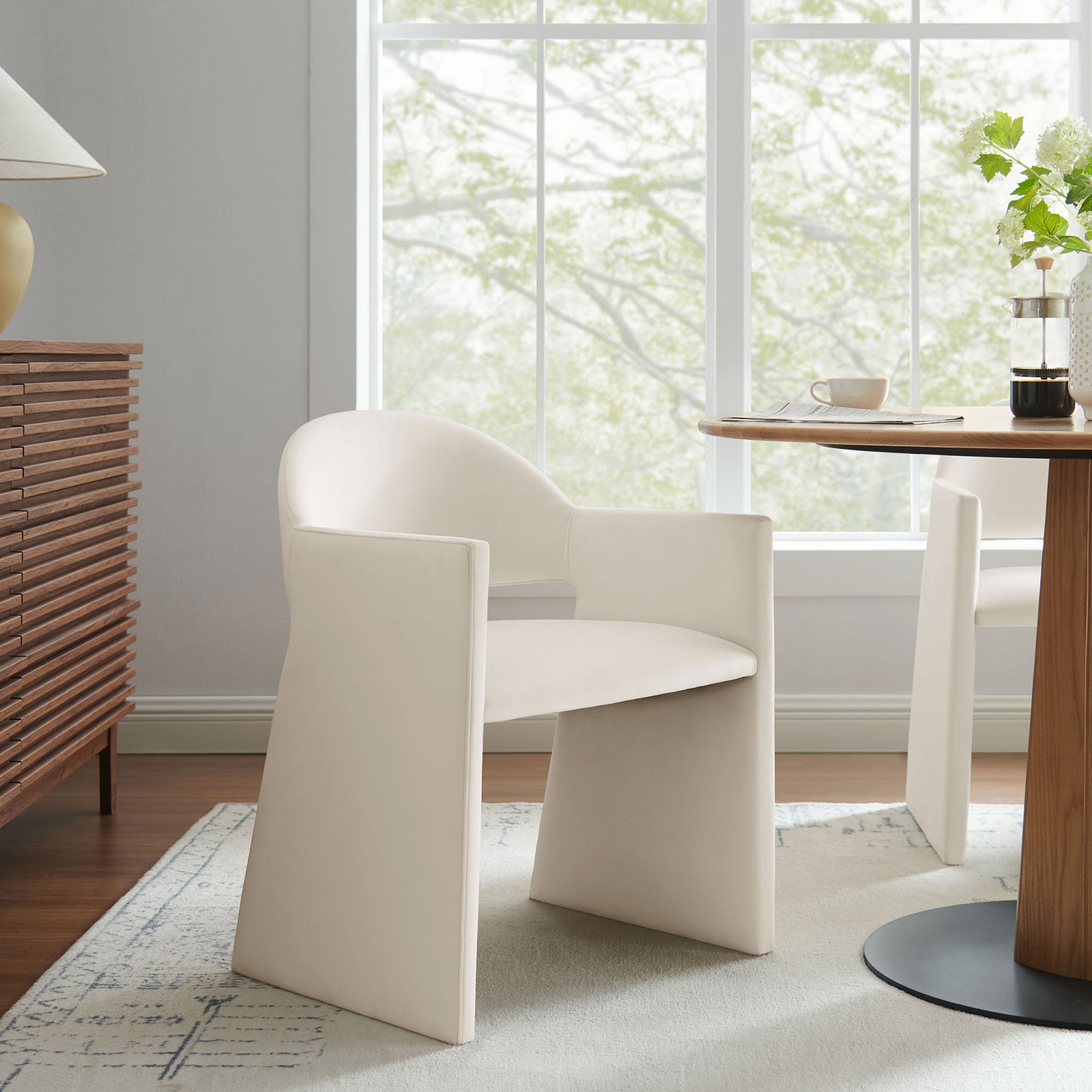 Talia alabaster velvet dining armchair styled in a bright dining room with wood table and credenza || EEI-7081-ALA || front_angle_room