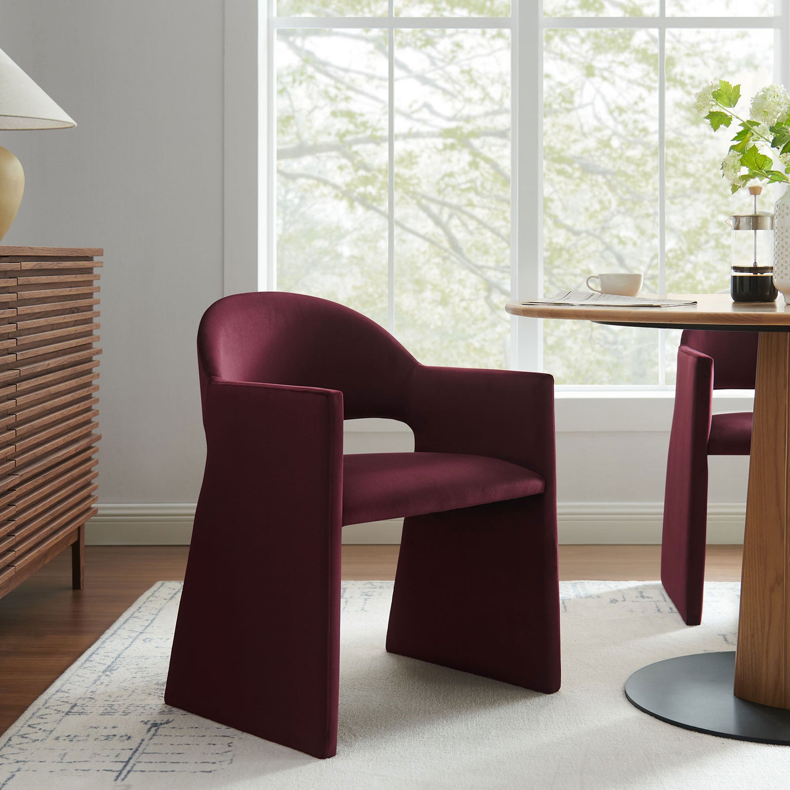 Mulberry velvet barrel-back dining armchair styled in a bright modern dining room with wood table || EEI-7081-MUL || front_angle_room