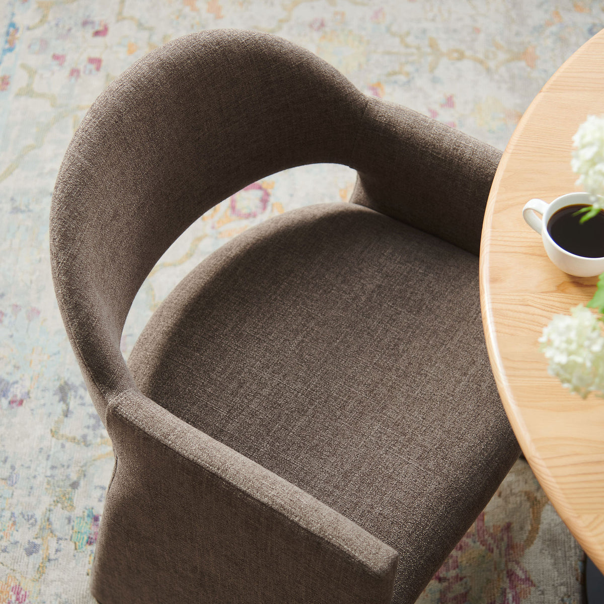 Mocha upholstered dining armchair styled at a round table on a patterned rug in a bright room || EEI-7082-MOC || detail_room