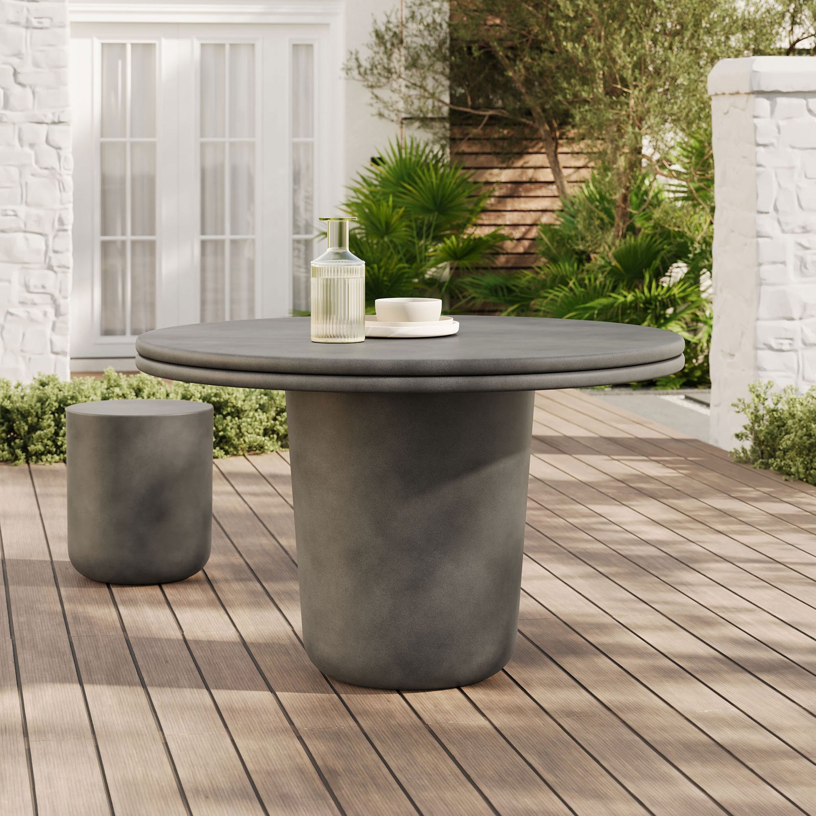 Gray concrete round dining table on a wood deck patio with matching accent stool and greenery || EEI-7087-GRY || front_angle_room