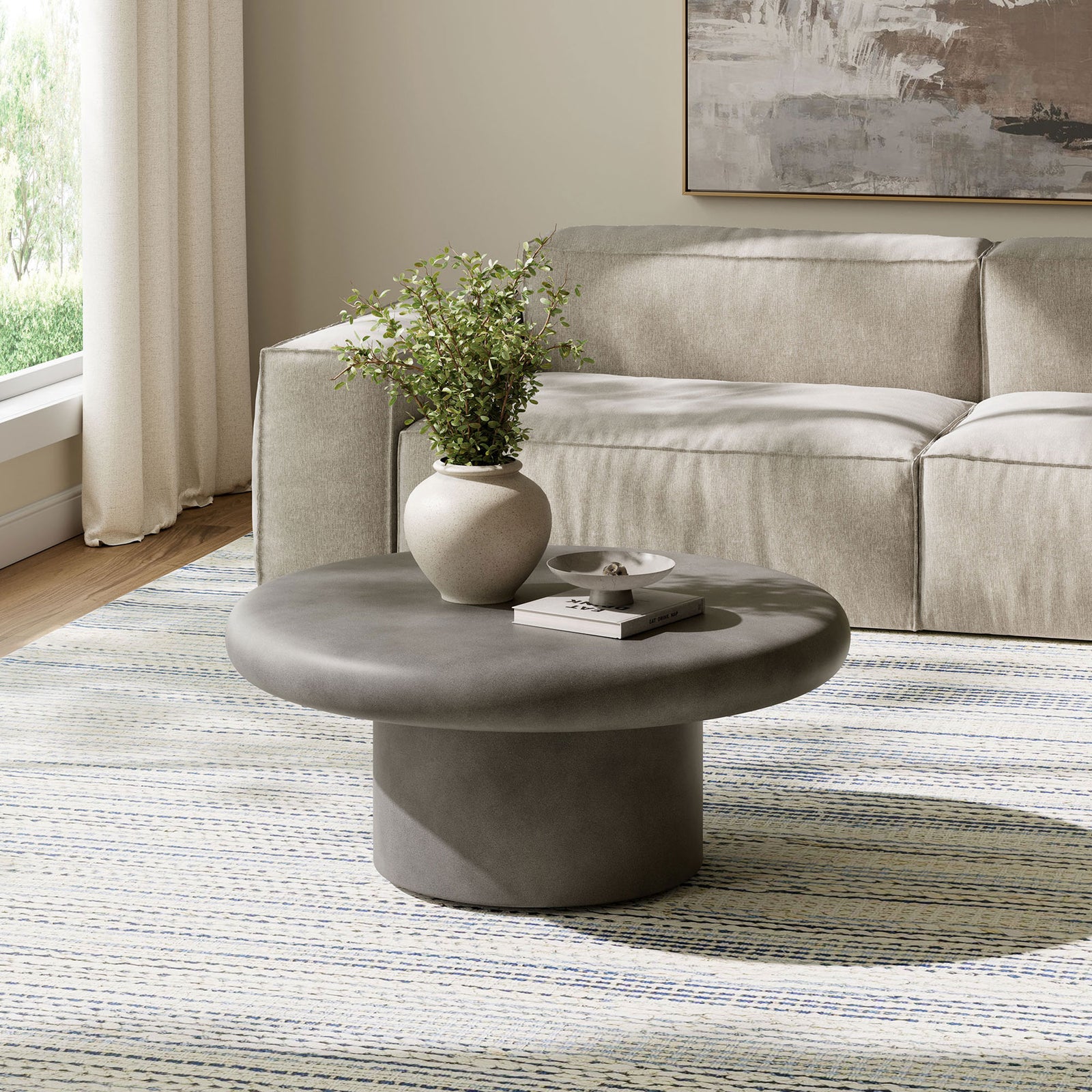 Gray concrete round coffee table with low cylindrical base anchoring a serene neutral living room seating area || EEI-7092-GRY || front_angle_room