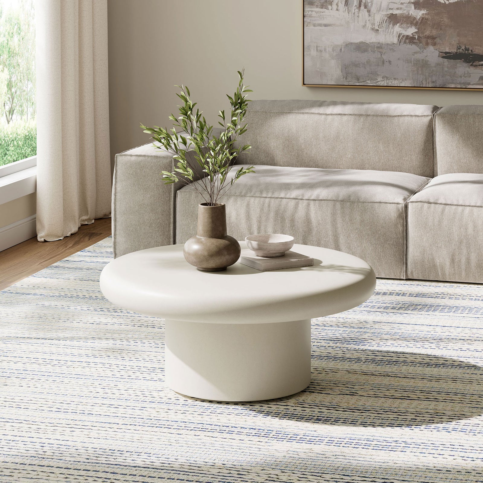 White concrete round coffee table with low cylindrical base brightening a calm, neutral living room seating area || EEI-7092-WHI || front_angle_room