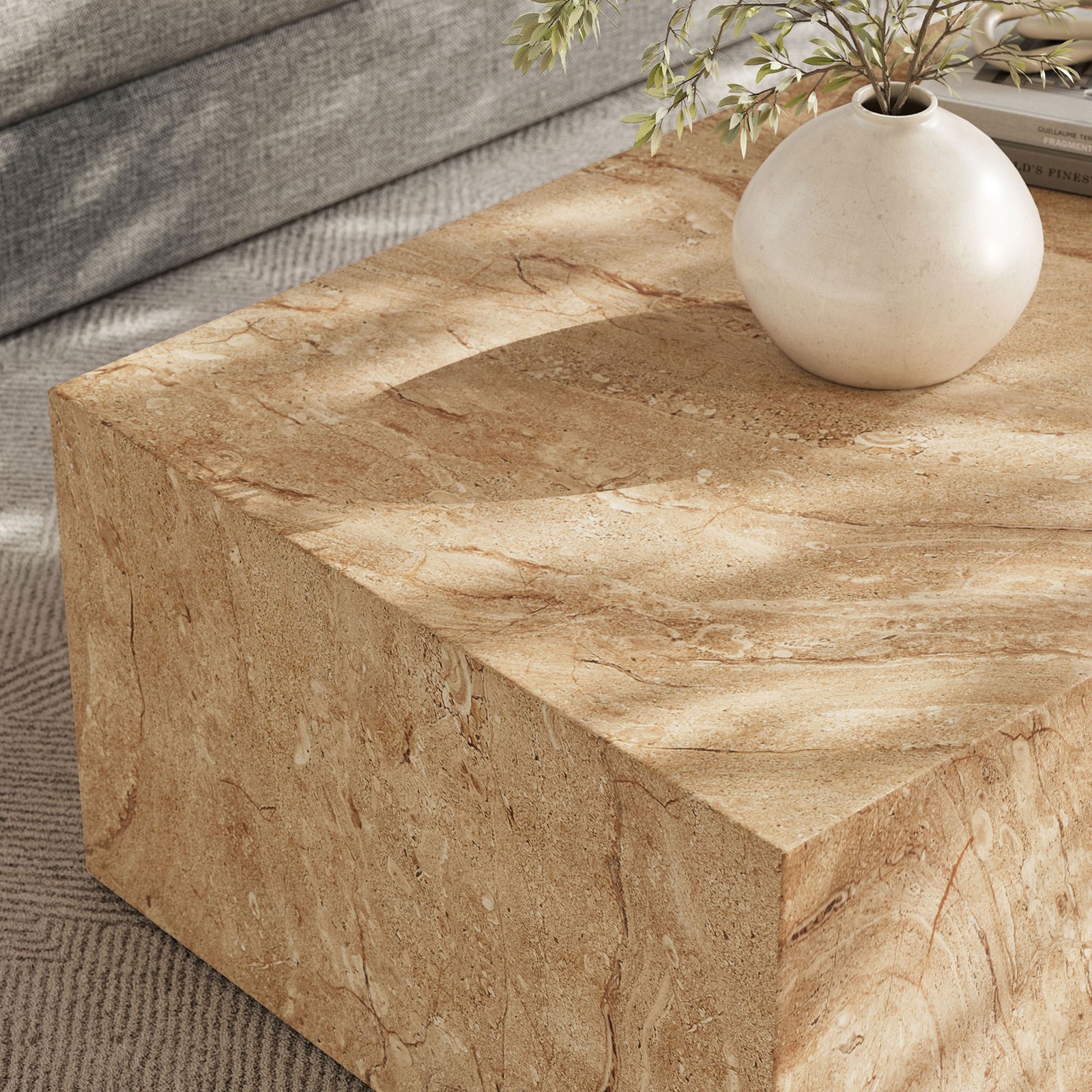 Travertine-look coffee table corner styled with a ceramic vase, revealing the smooth faux stone texture and warm tones || EEI-7095-TRV || detail_room