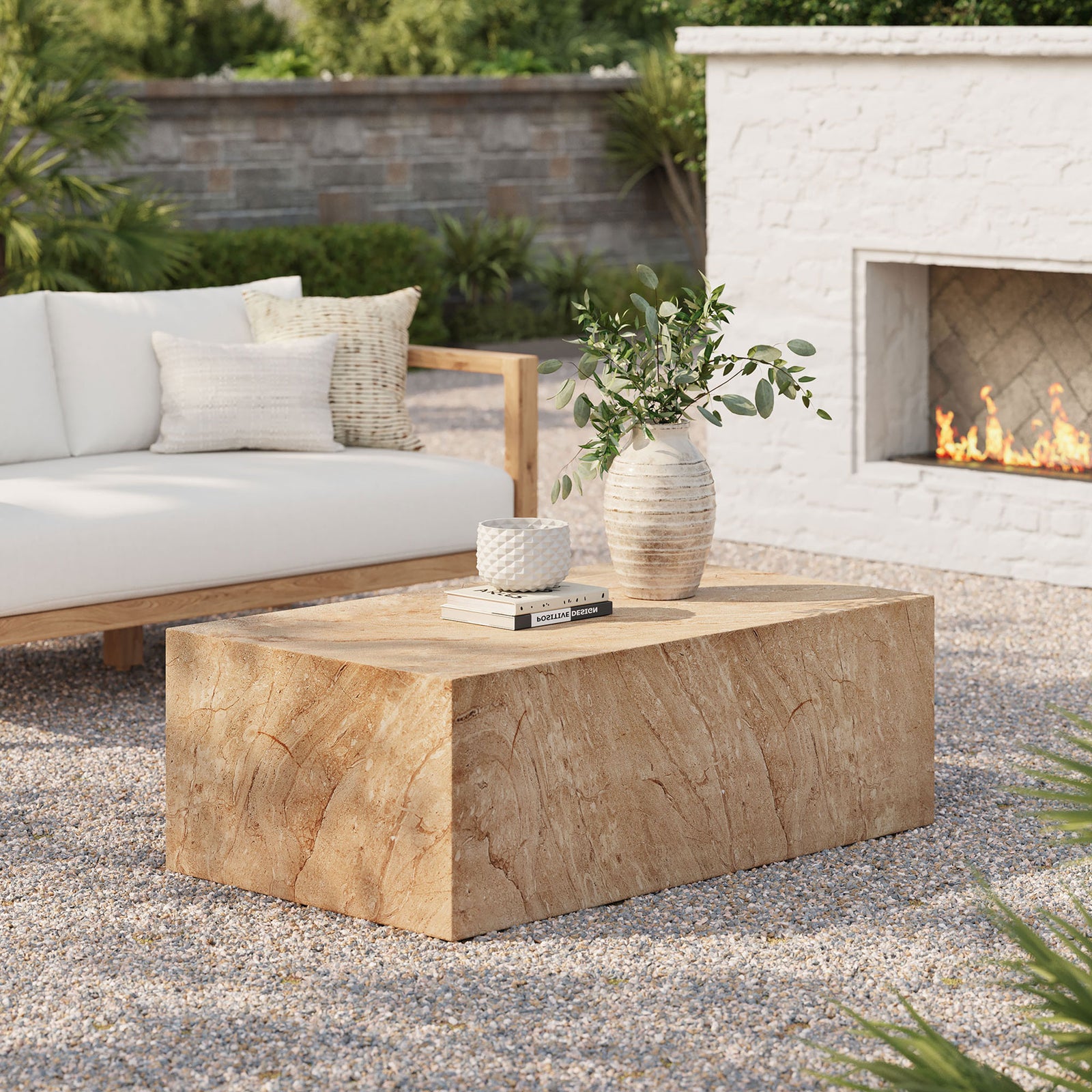 Travertine-look concrete coffee table completes a relaxed outdoor lounge beside neutral seating and a glowing fireplace || EEI-7095-TRV || front_angle_room