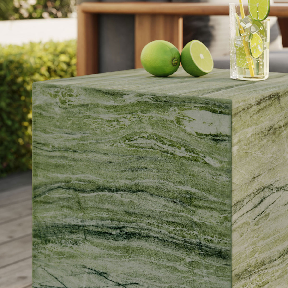 Green faux stone side table used as an outdoor drink perch, showing organic veining and smooth edges. || EEI-7096-GRN || detail_room