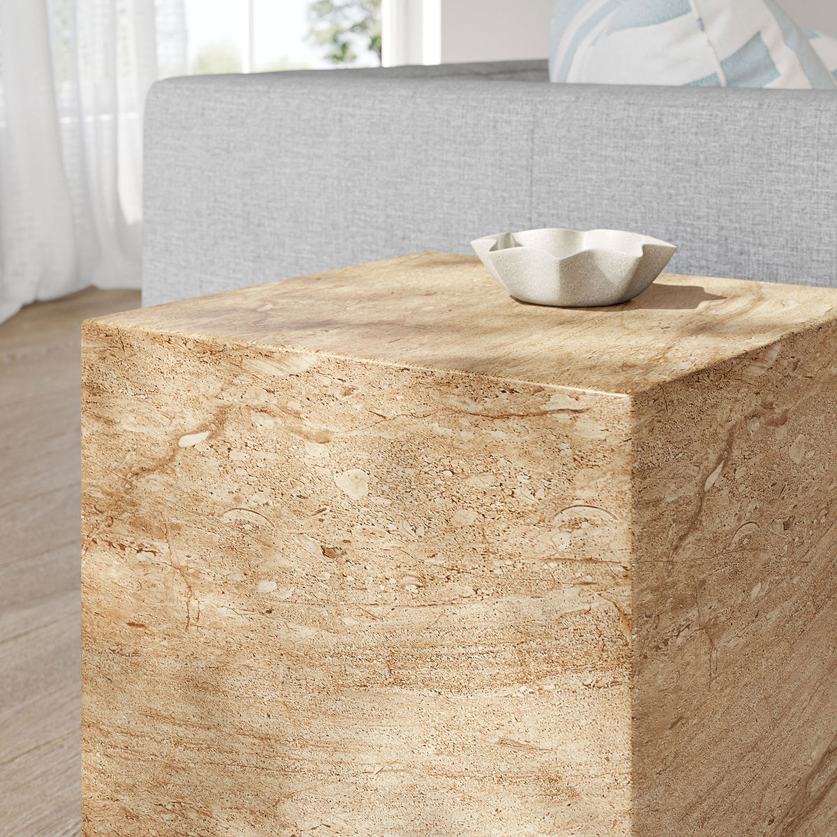 Travertine-look side table styled in a serene living room with a sculptural ceramic dish. || EEI-7096-TRV || detail_room