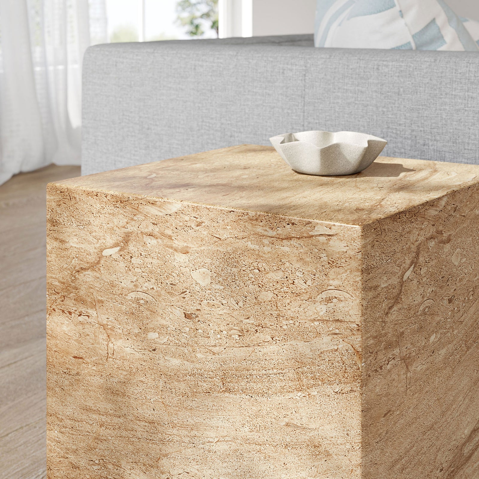 Travertine-look side table styled in a serene living room with a sculptural ceramic dish. || EEI-7096-TRV || detail_room