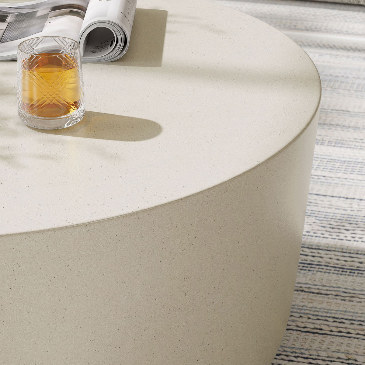 Detail of the white concrete coffee table surface with a drink, underscoring its smooth curved edge || EEI-7099-WHI || detail_room