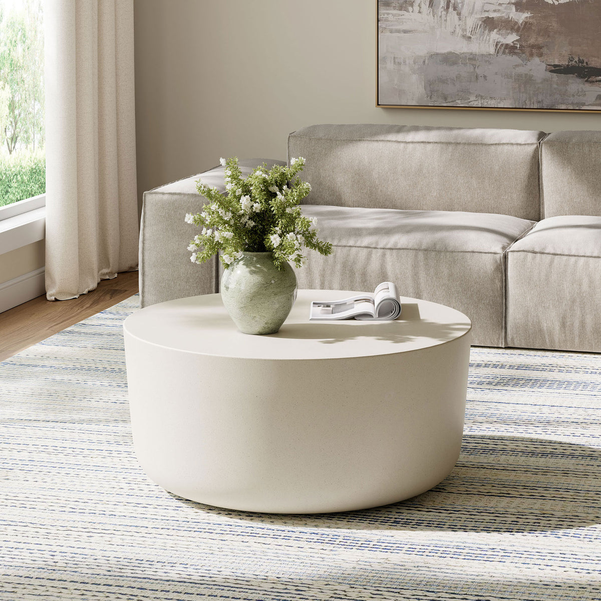 White concrete drum coffee table anchoring a contemporary living room with airy, minimalist style || EEI-7099-WHI || front_angle_room
