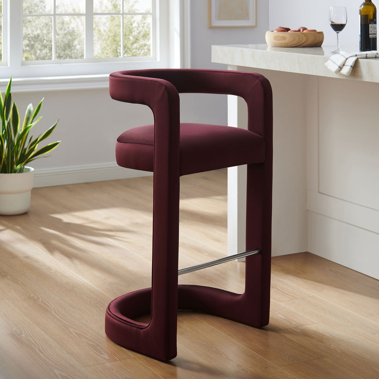 A modern velvet bar stool in deep mulberry brings sculptural elegance to your kitchen bar. || EEI-7108-MUL || front_angle_room