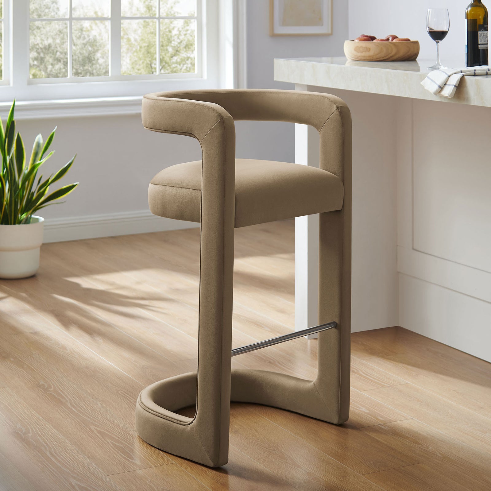Stylish taupe velvet bar stool refreshes the kitchen with modern curves and a steel footrest || EEI-7108-TAU || front_angle_room