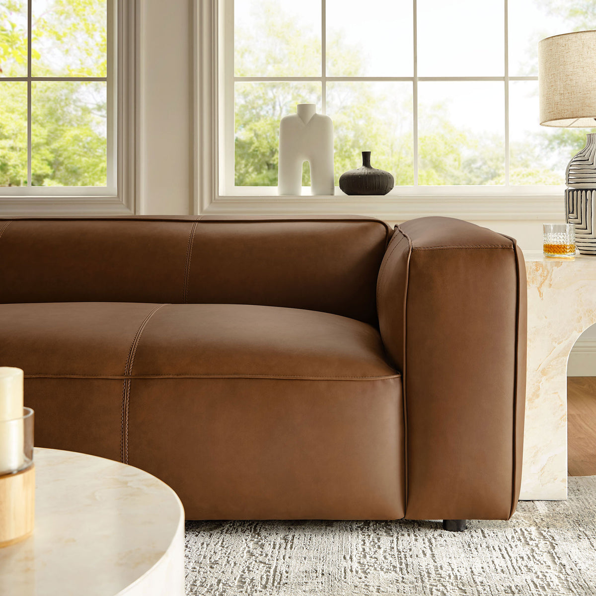 Coffee vegan leather sofa arm styled with decor in a bright windowed living room || EEI-7119-COF || detail_room
