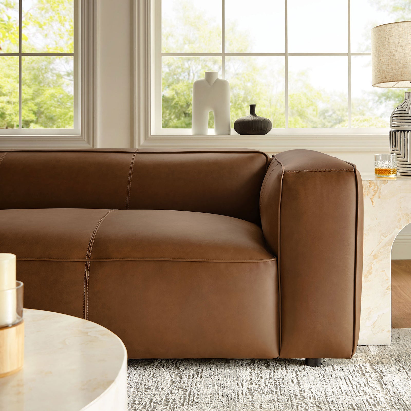 Coffee vegan leather sofa arm styled with decor in a bright windowed living room || EEI-7119-COF || detail_room