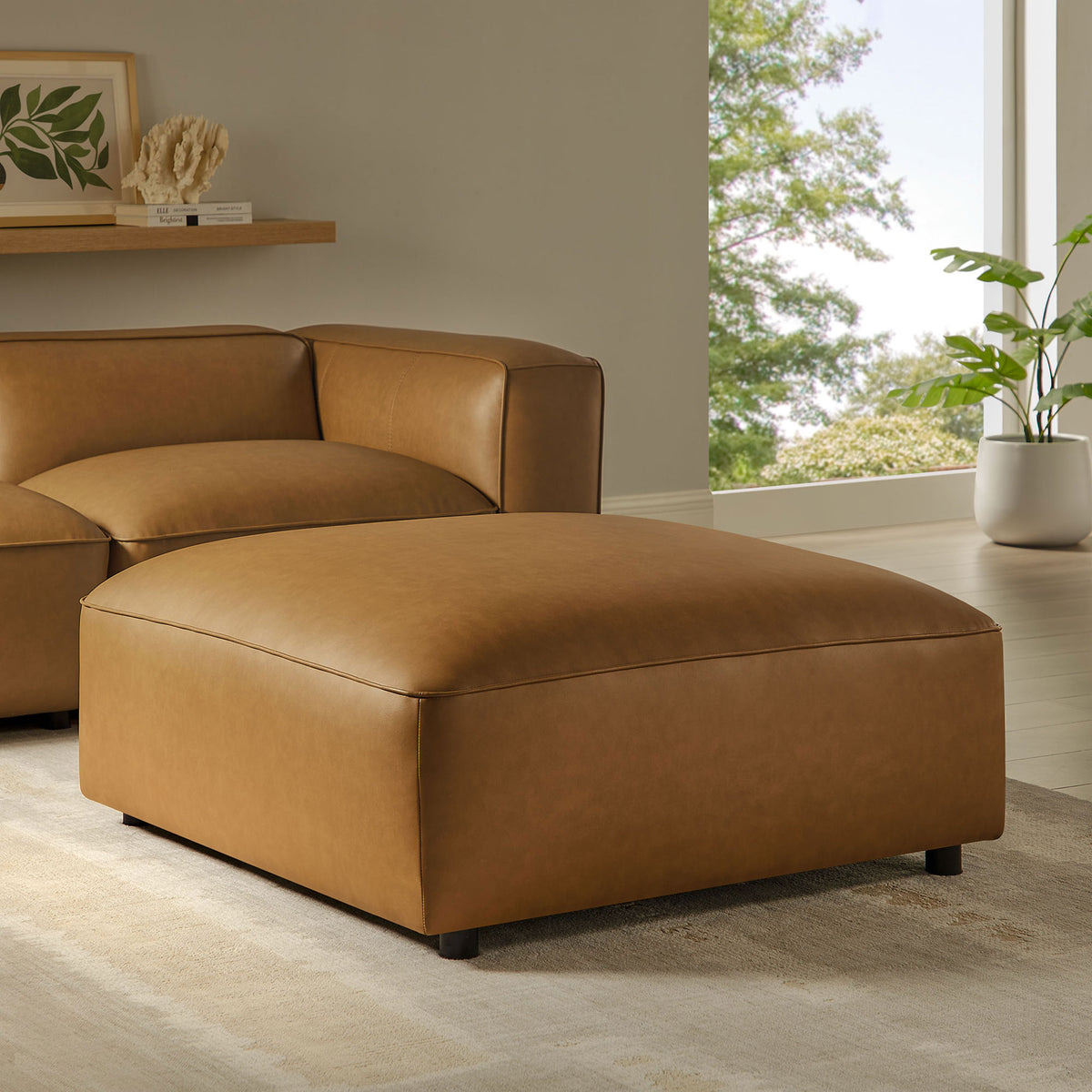 Camel vegan leather ottoman styled in a modern living room with coordinating modular seating || EEI-7125-CAM || front_angle_room