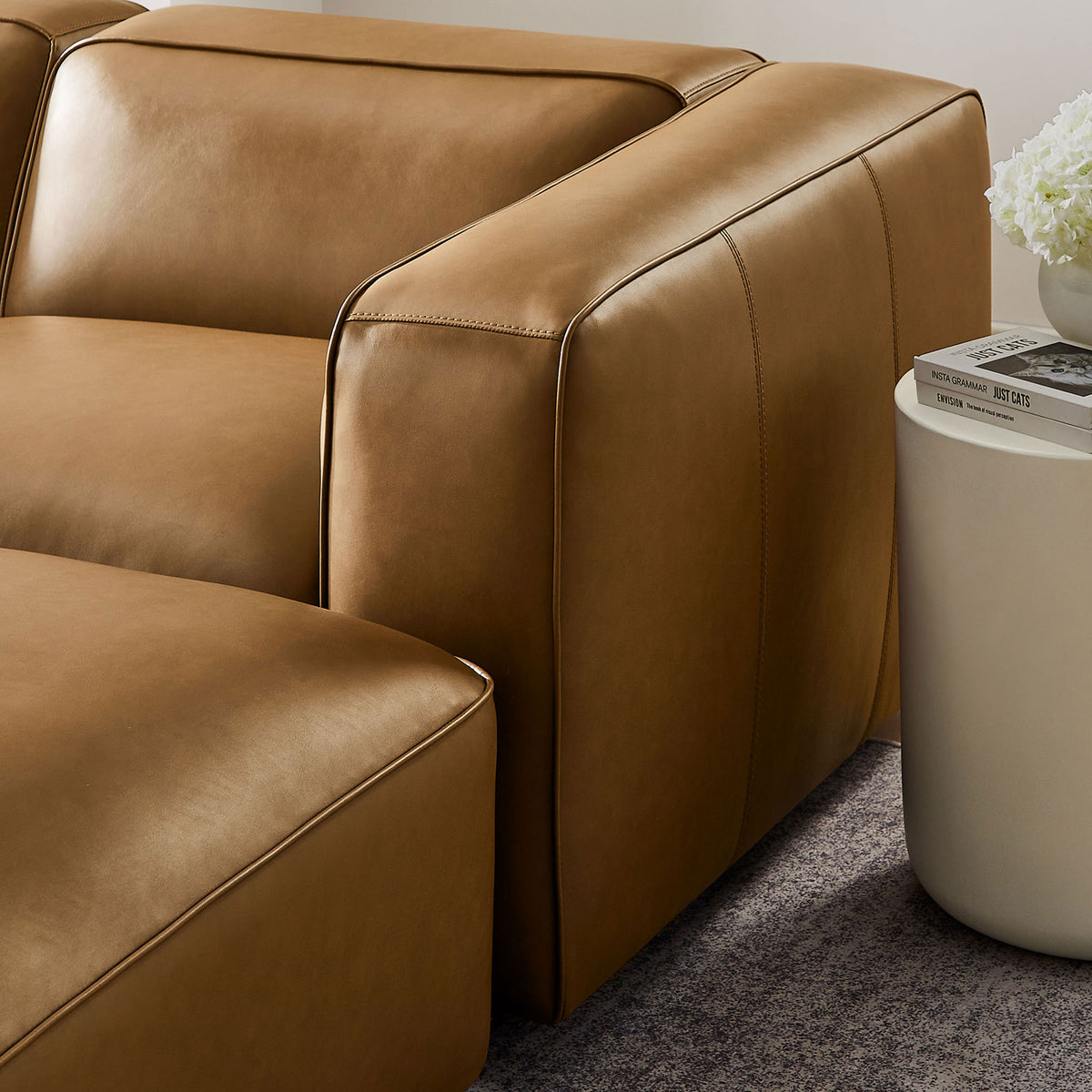 Chunky arm and tailored stitching of the camel vegan leather modular sofa styled next to a modern side table || EEI-7131-CAM || detail_room