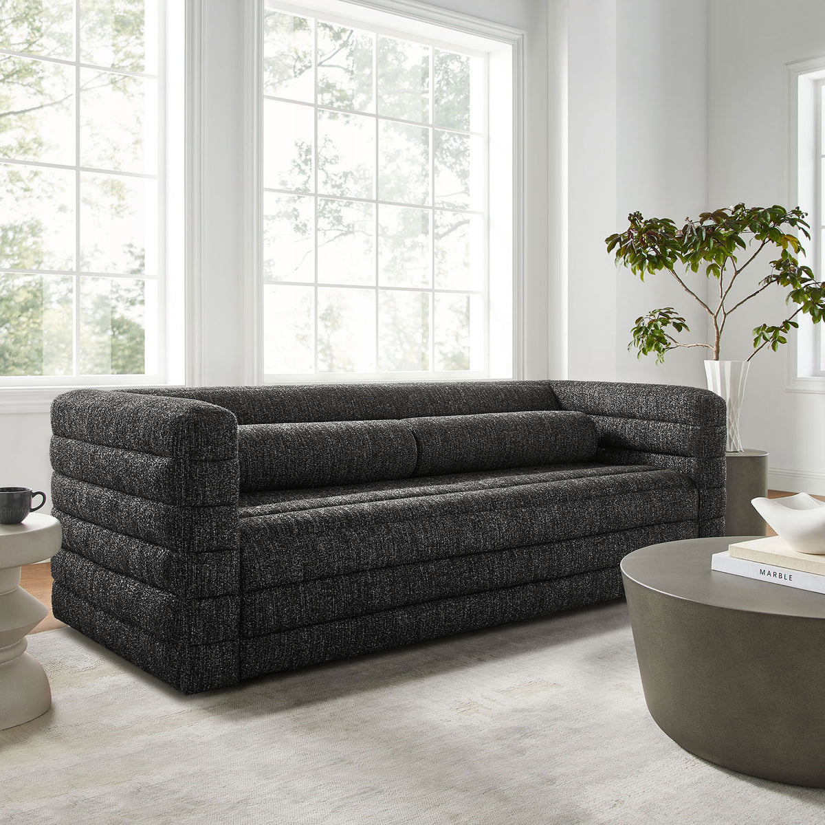 Charcoal boucle Relle sofa anchors a bright living room with layered channel tufting and plush bolster pillows || EEI-7136-CHA || front_angle_room