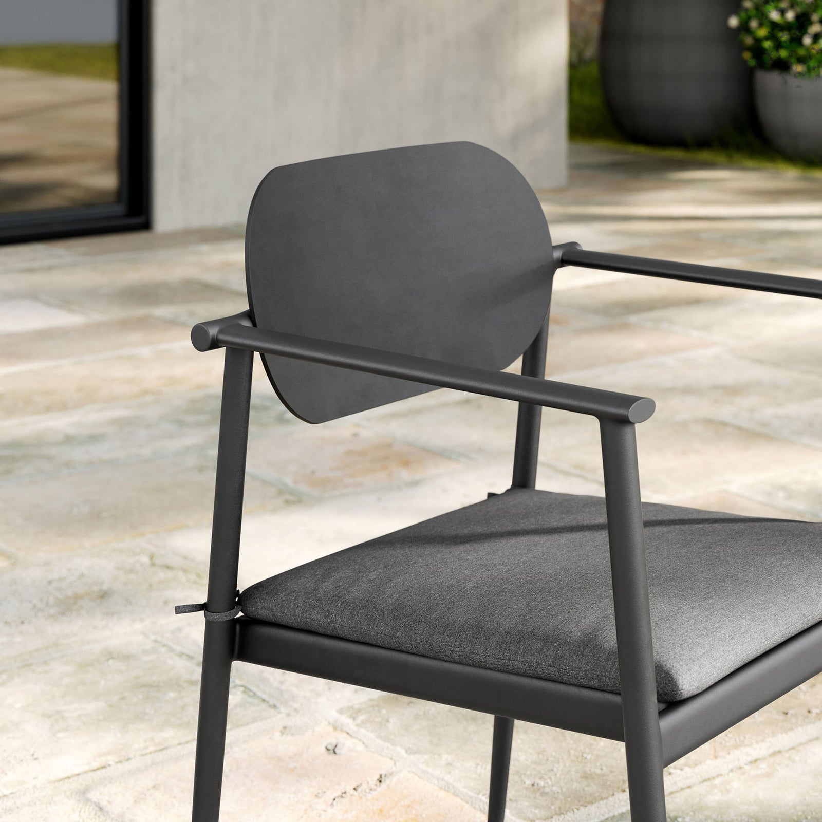 Close up of charcoal patio armchair backrest, slim arms, and cushioned seat on a modern stone terrace || EEI-7148-CHA-CHA || detail_room