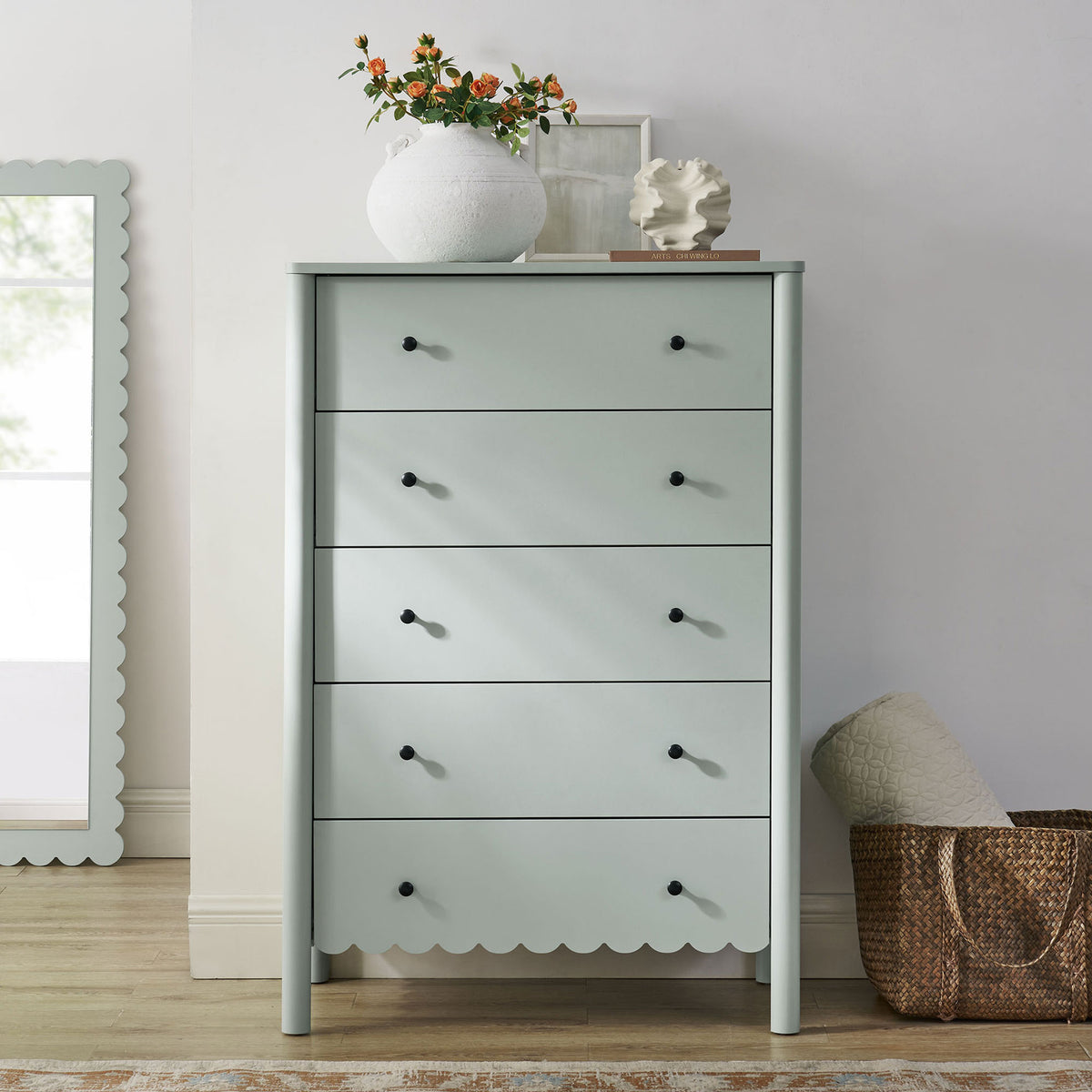Emmeline sage green 5-drawer chest styled with decor beside a scalloped mirror in a bright bedroom || EEI-7156-SGE || front_room