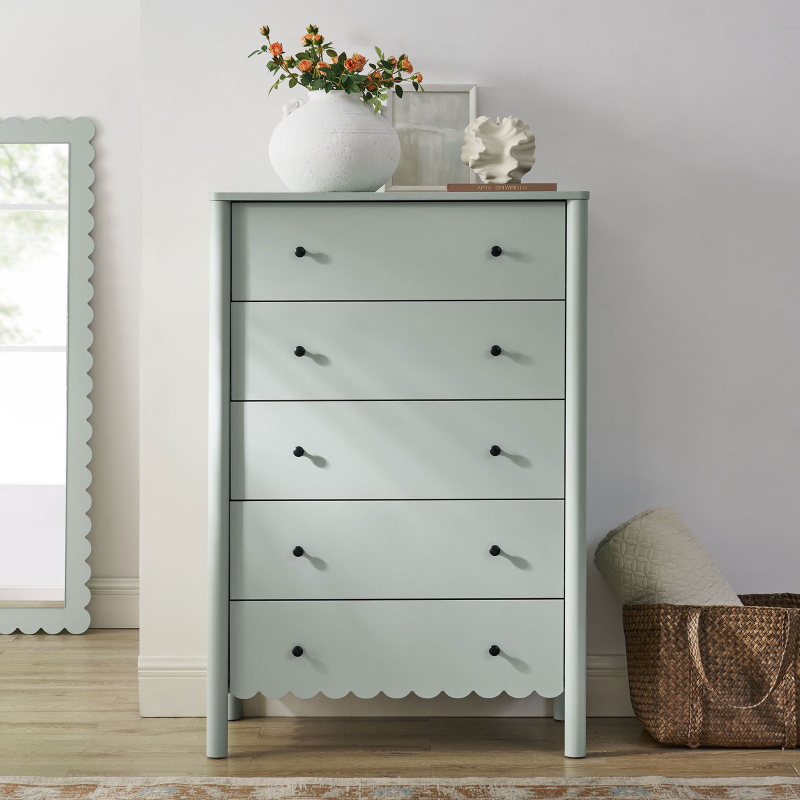 Emmeline sage green 5-drawer chest styled with decor beside a scalloped mirror in a bright bedroom || EEI-7156-SGE || front_room