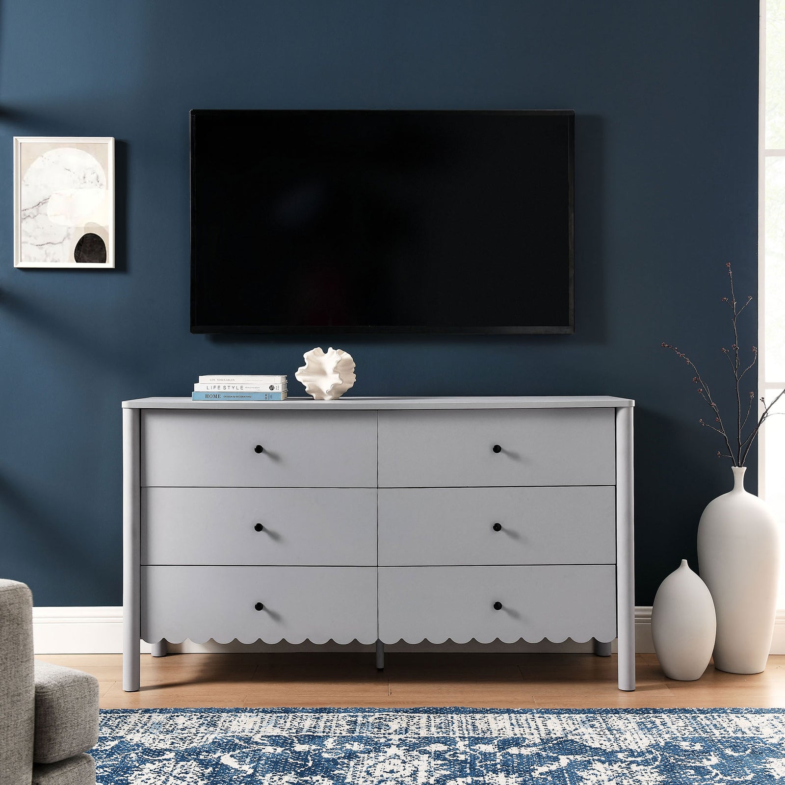 Light gray scalloped dresser styled as a TV console in a modern living room setting. || EEI-7157-LGR || front_room