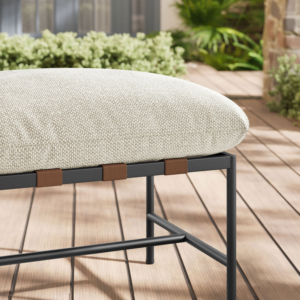 Ivory boucle cushion and strap accents of the outdoor ottoman contrasted against warm deck boards and greenery || EEI-7161-IVO || detail_room
