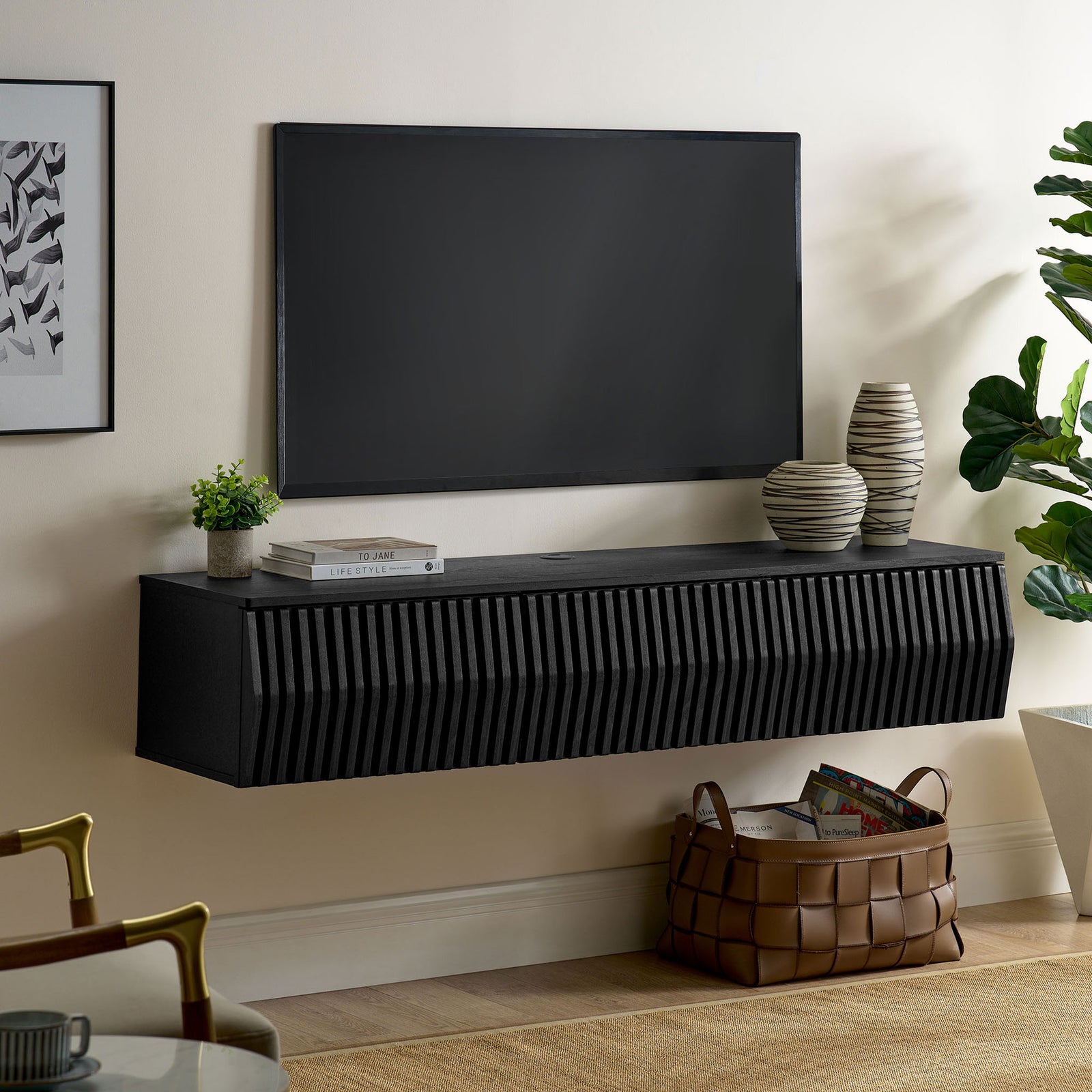Black floating TV console installed beneath a wall-mounted screen in a contemporary living room || EEI-7164-BLK || front_angle_room