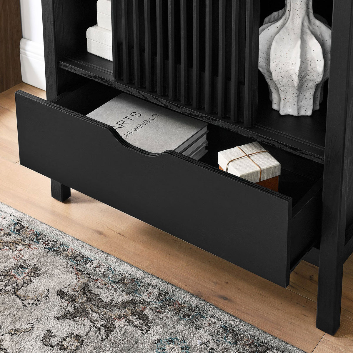 Open drawer of the black cabinet neatly storing books and decor in a modern room. || EEI-7167-BLK || storage_open_room