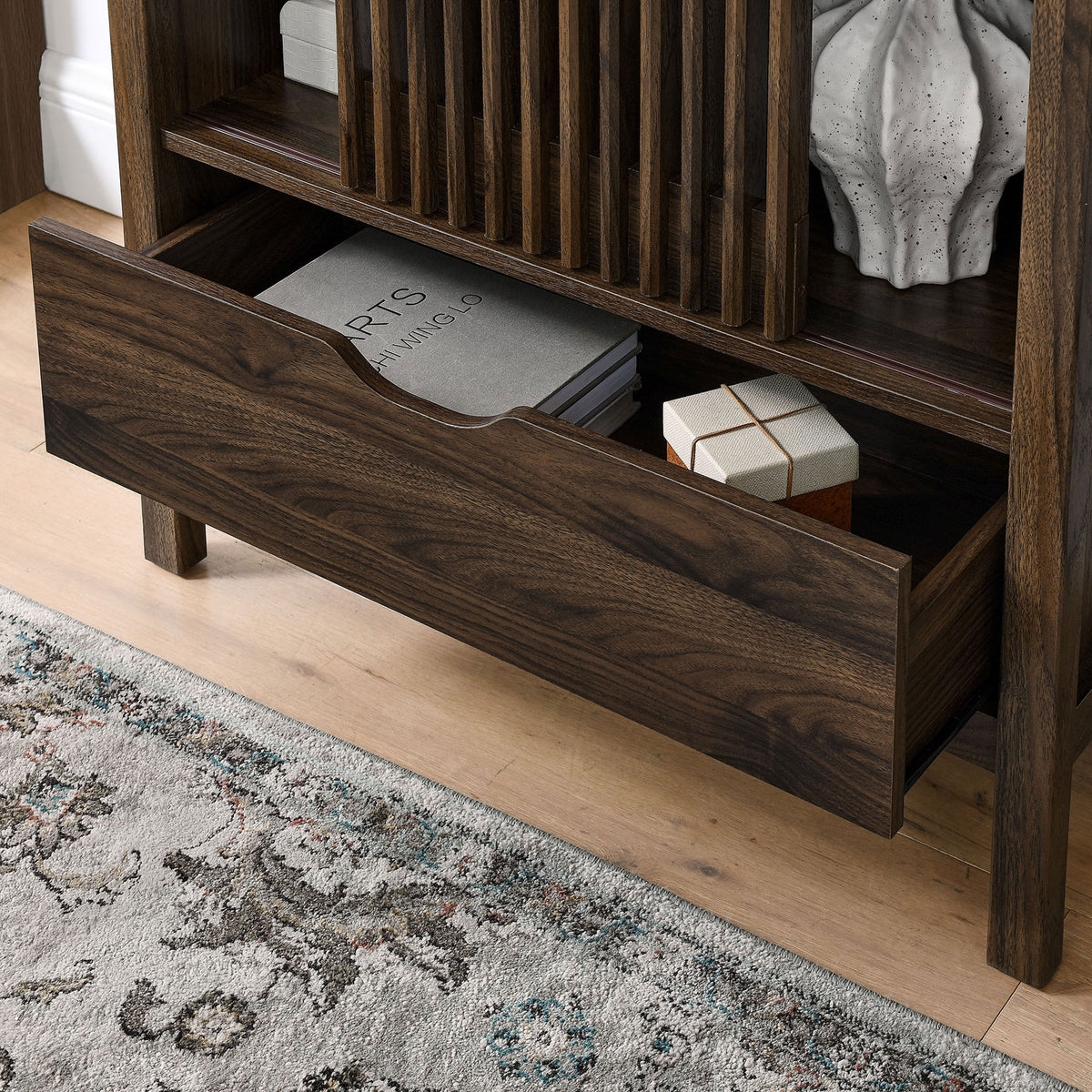Open drawer of the walnut cabinet neatly storing books and decor in a modern room. || EEI-7167-WAL || storage_open_room