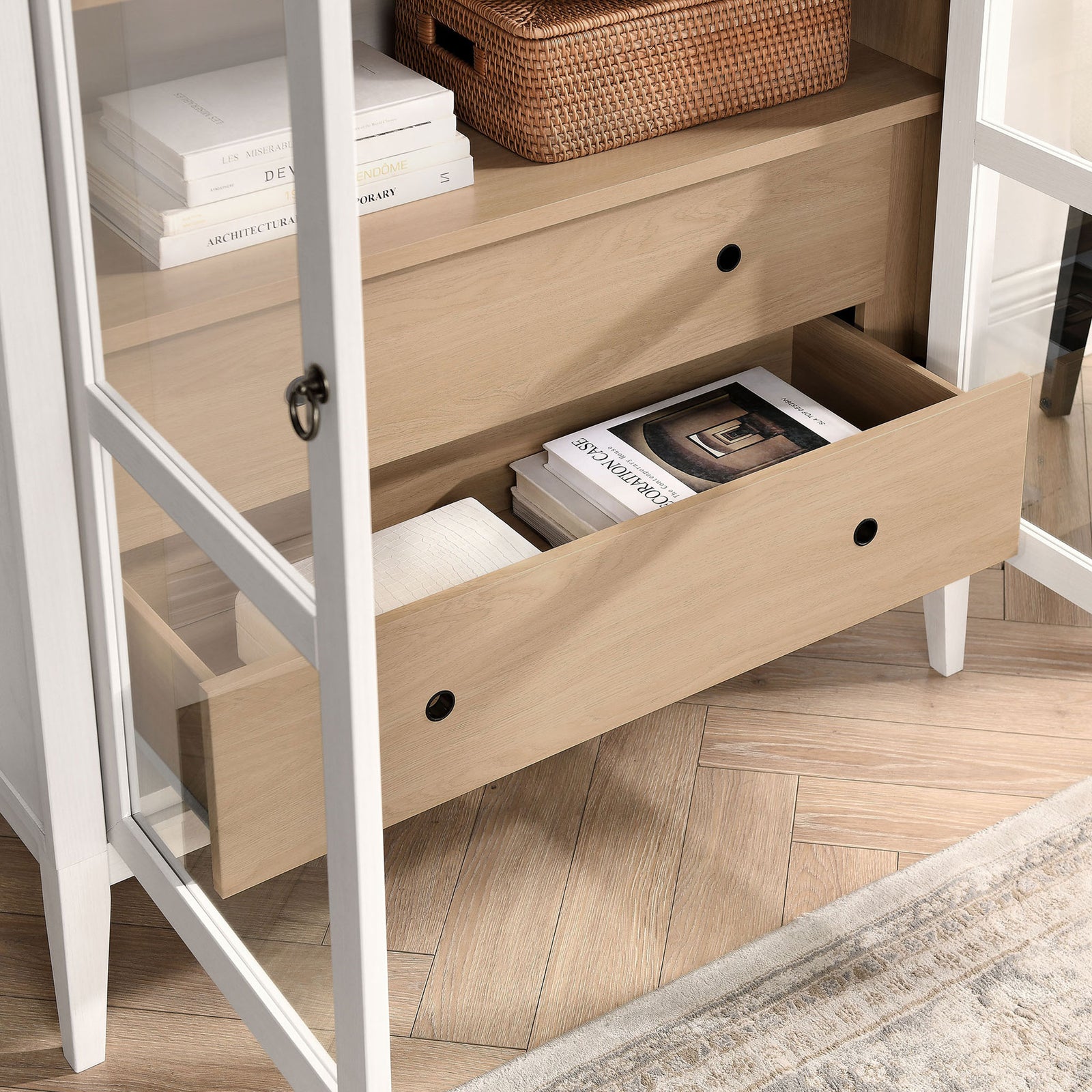 Lower drawer of the ivory oak cabinet organizing books and textiles on herringbone flooring || EEI-7168-IVO-OAK || storage_open_room