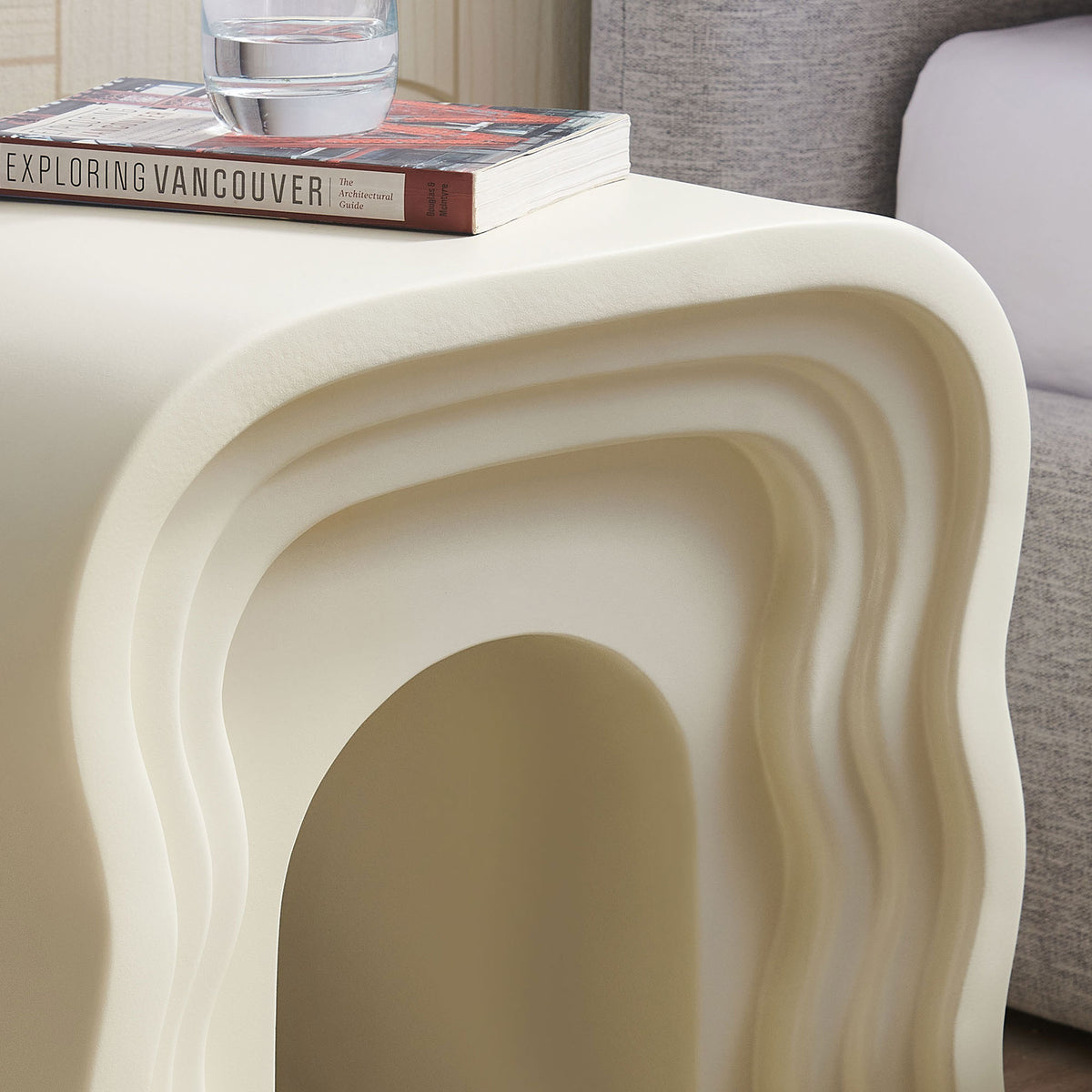 Ivory squiggle side table styled with books and a drink to show everyday use beside the bed || EEI-7171-IVO || detail_room
