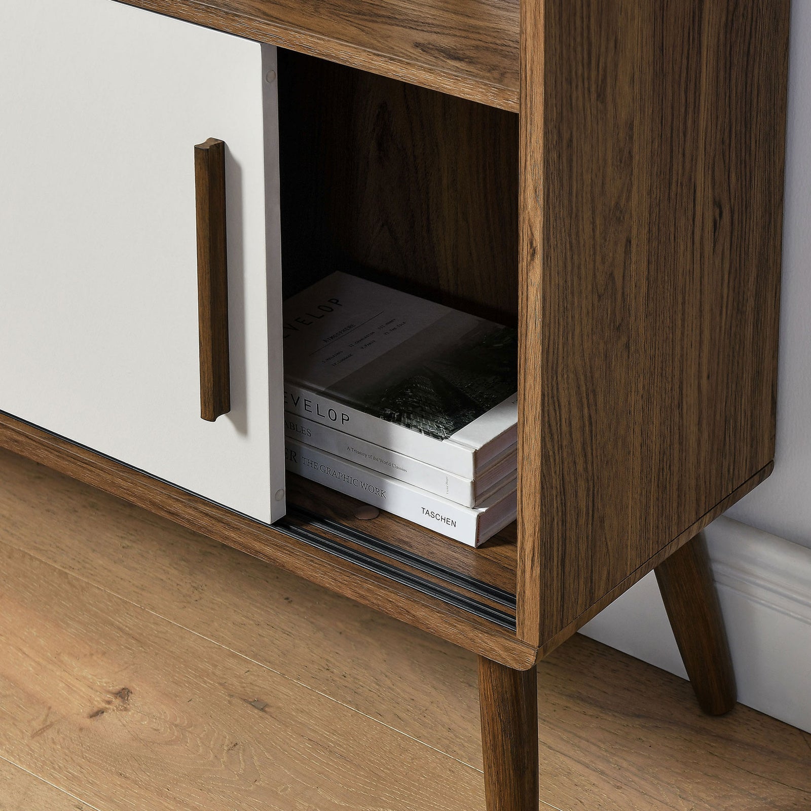 Concealed compartment neatly tucks away books behind the smooth-gliding white door. || EEI-7193-WAL-LIN || storage_open_room