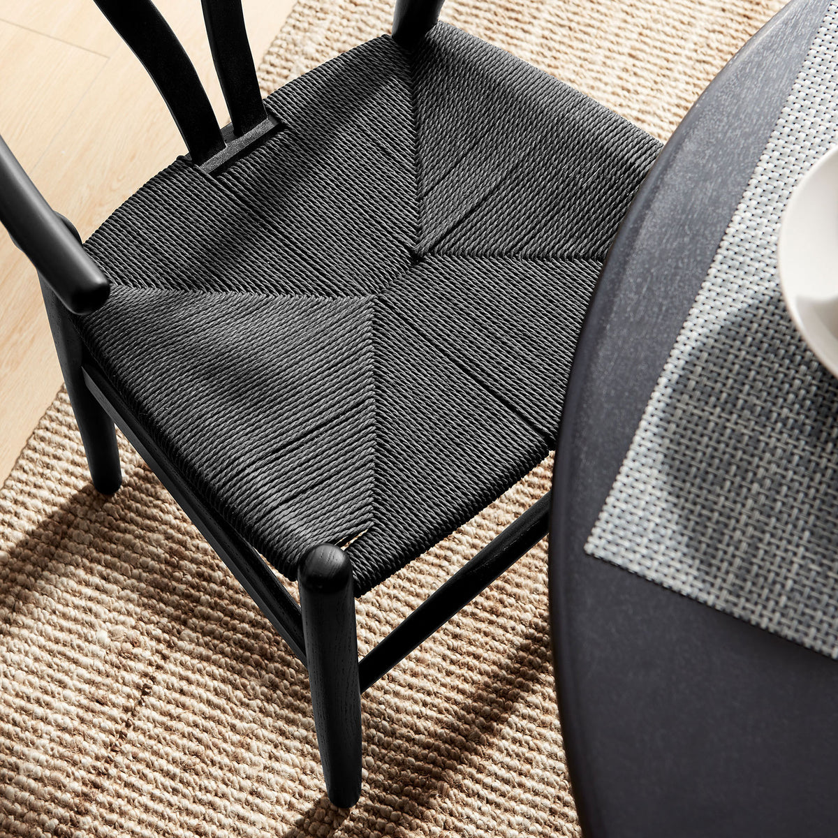 Overhead view of the black woven rope seat paired with a textured rug and dining table || EEI-7200-BLK-BLK || detail_room
