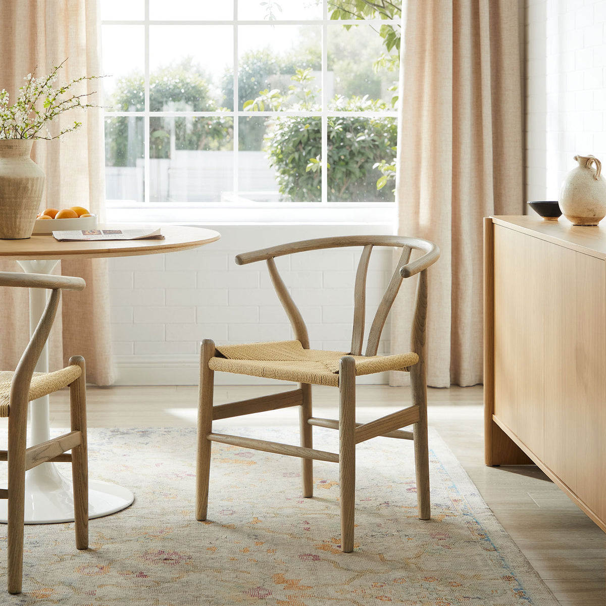 Amish gray wood dining chair in a bright modern dining room beside a round pedestal table and sideboard || EEI-7200-GRY || front_angle_room
