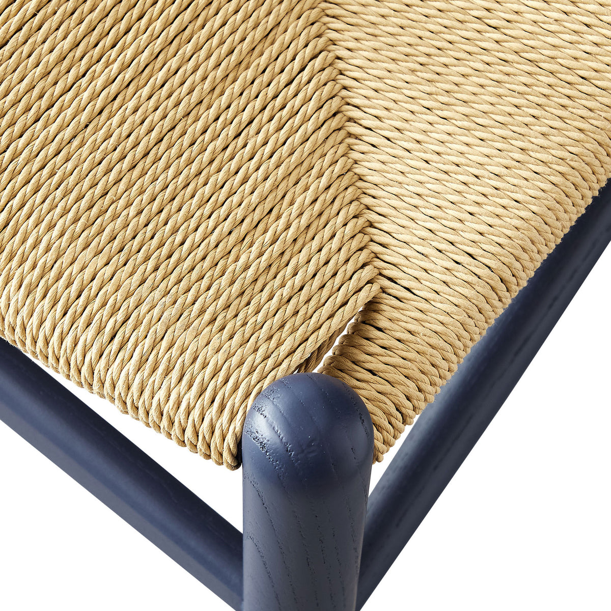 Tightly woven paper rope seat pattern meeting a rounded midnight blue wood corner post. || EEI-7200-MID || detail_studio