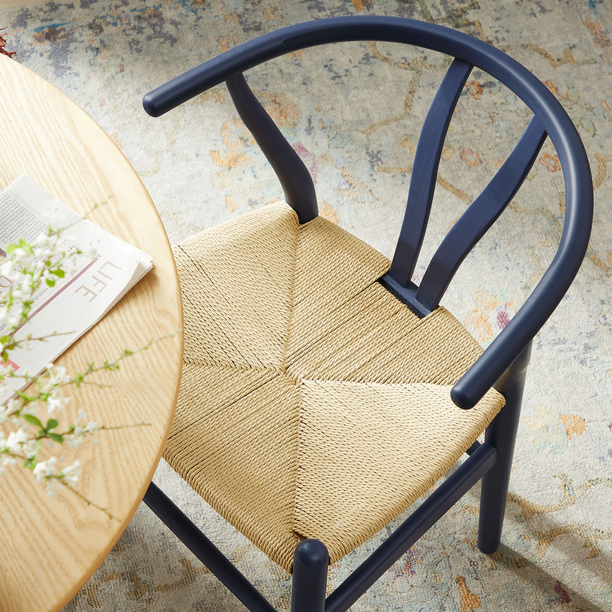 Amish dining chair tucked beside a round wood table, highlighting the woven rope seat and curved back. || EEI-7200-MID || top_angle_room