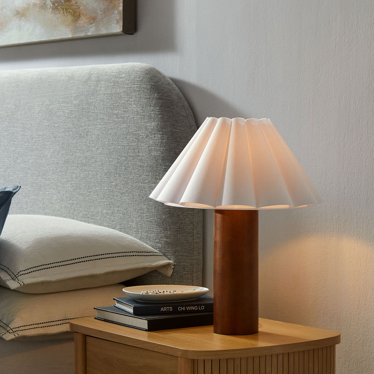 Flora table lamp softly illuminating bedroom with warm glow through pleated shade || EEI-7214-WAL || front_angle_on_room