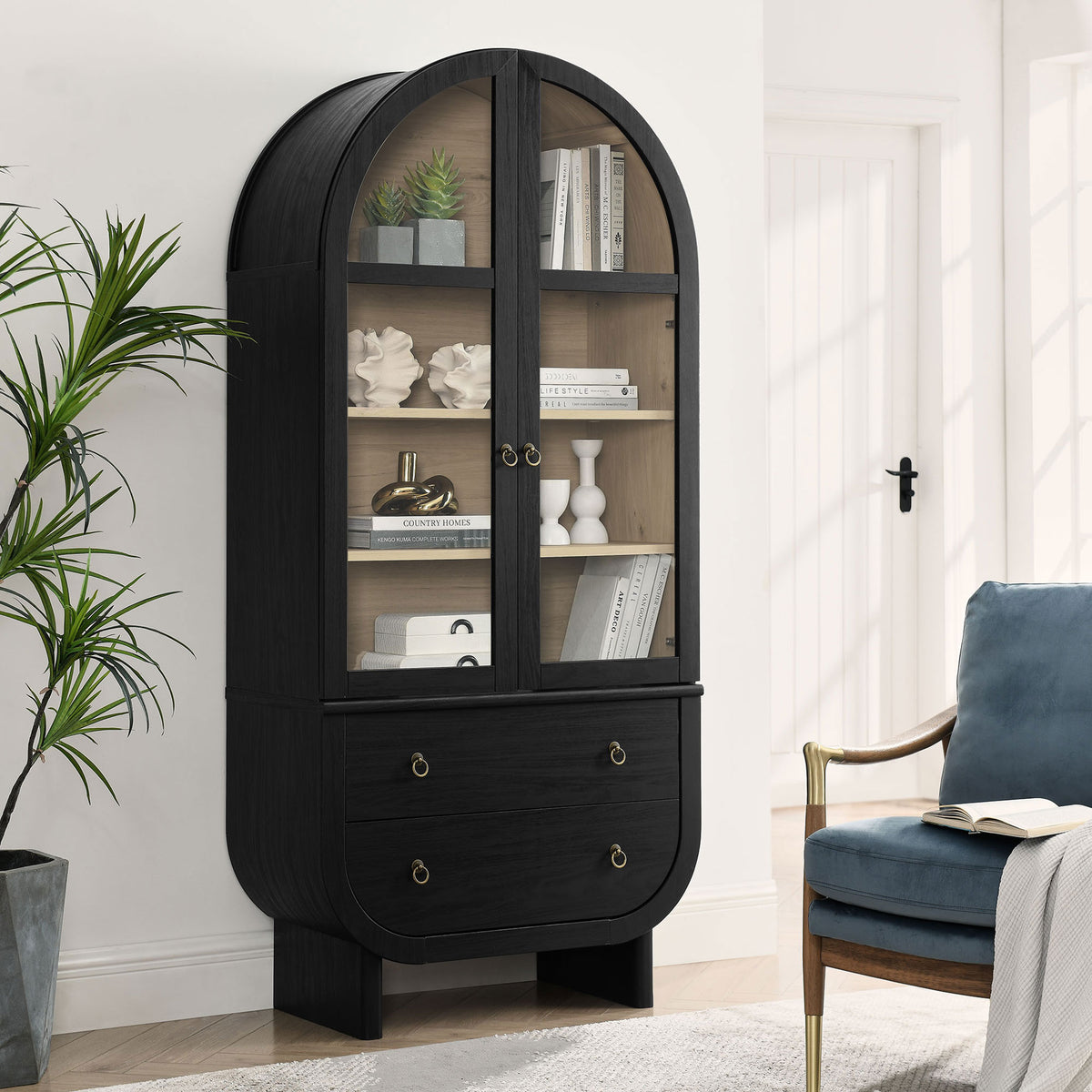 Nyx black arched display cabinet styled with books and sculptural decor beside a cozy accent chair || EEI-7216-BLK-LOA || front_angle_room
