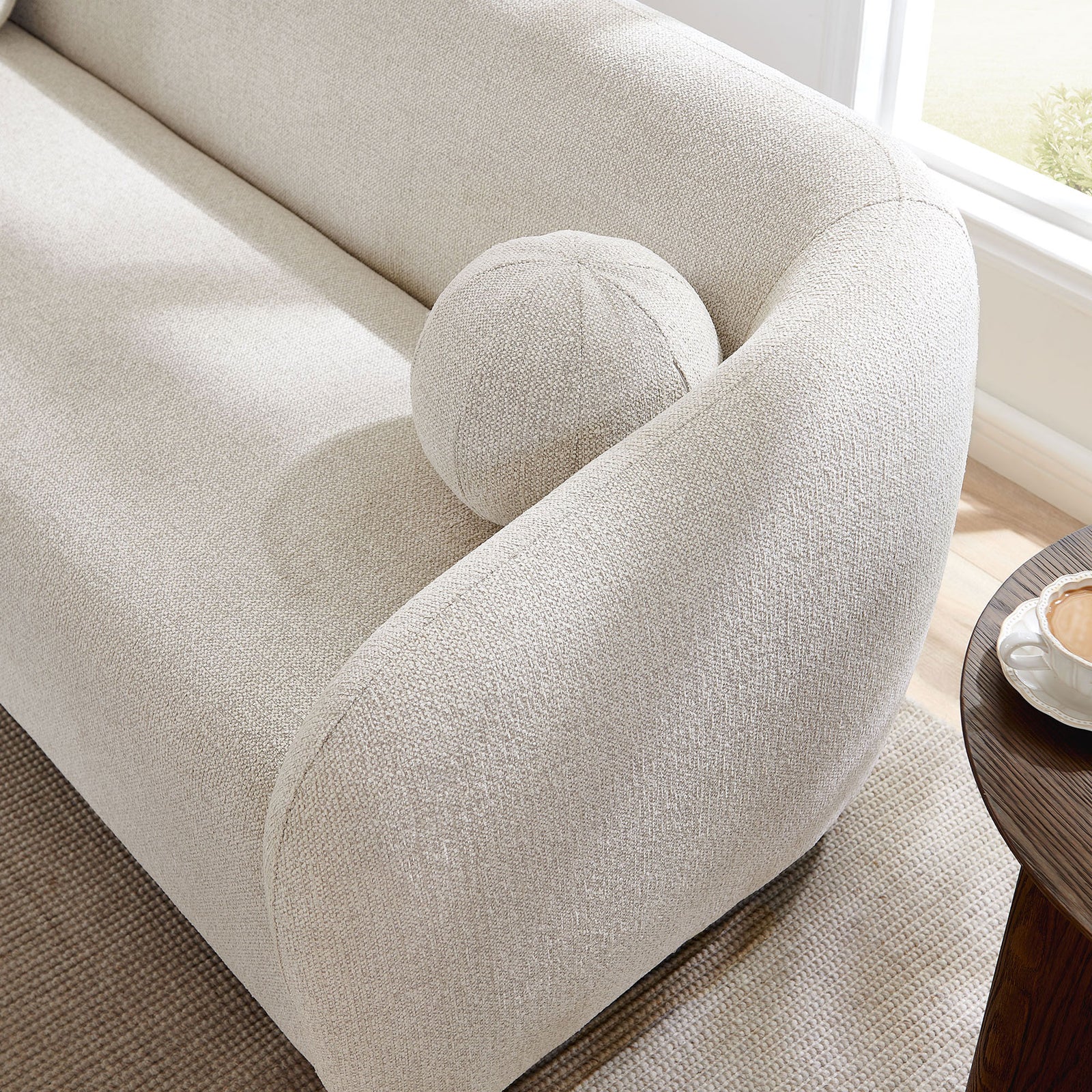 Detail of ball pillow nestled in curved sofa arm in a bright contemporary living room || EEI-7217-DOV || detail_room