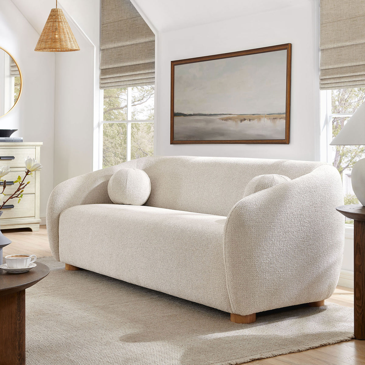 Curved dove gray sofa styled in an airy living room with neutral rug and wood accents || EEI-7217-DOV || front_angle_room