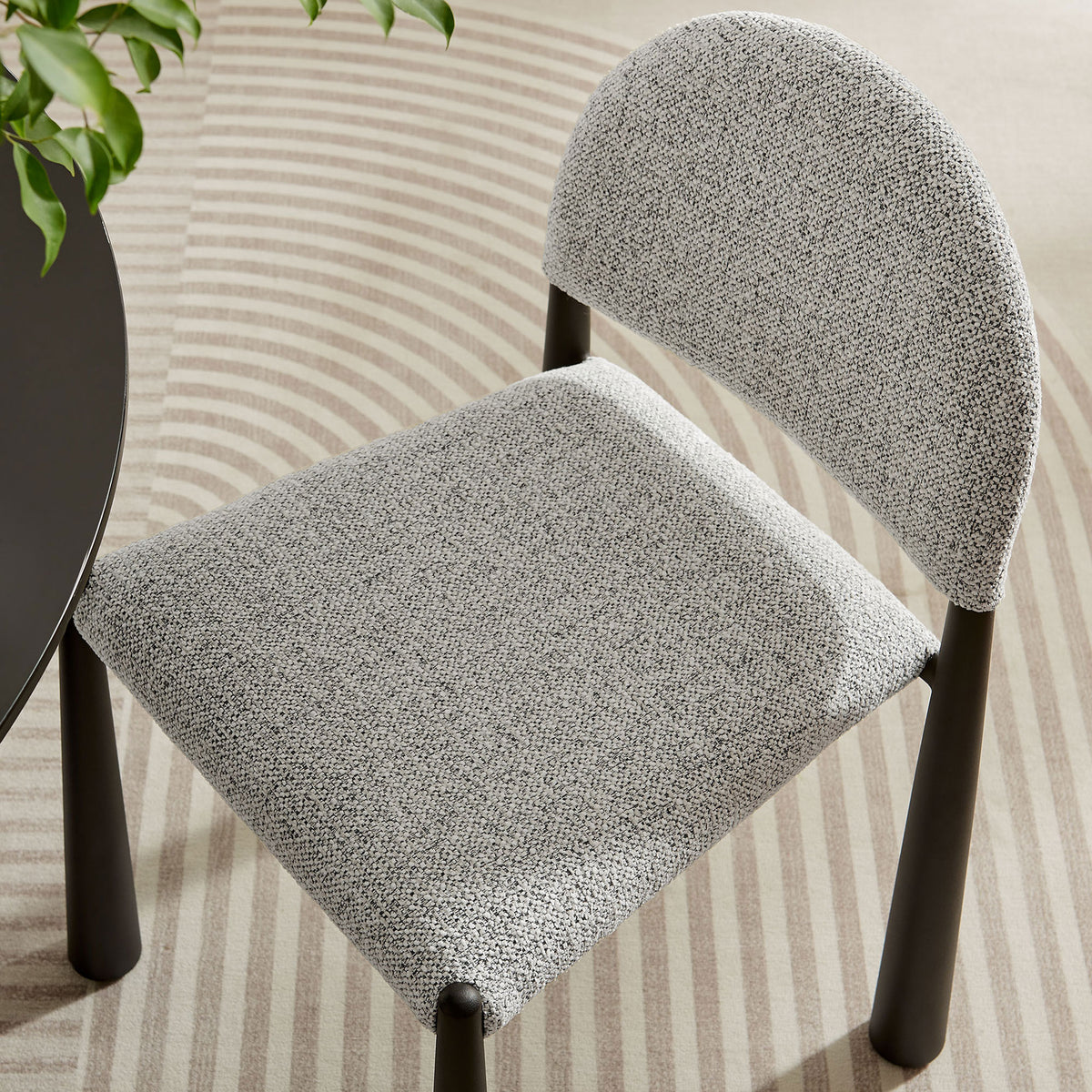 Hayley chair in a modern dining space emphasizing its soft textured seat and gently curved backrest || EEI-7220-BLK-CAM || detail_room