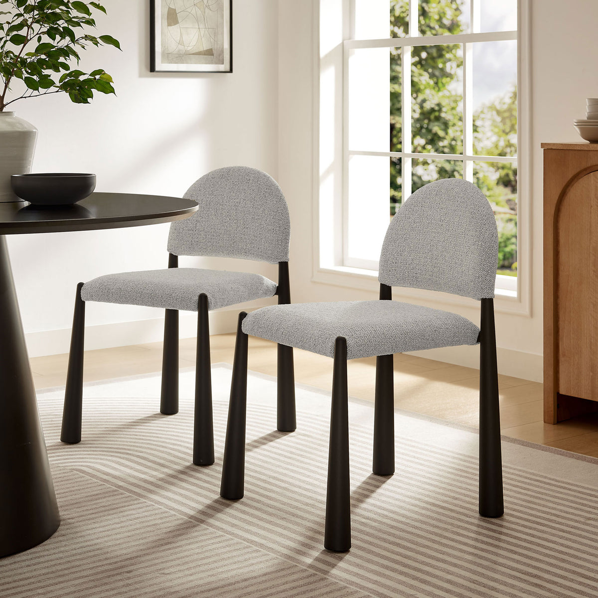 Pair of Hayley dining chairs with boucle-style seats and black legs styled around a contemporary dining table || EEI-7220-BLK-CAM || front_angle_room