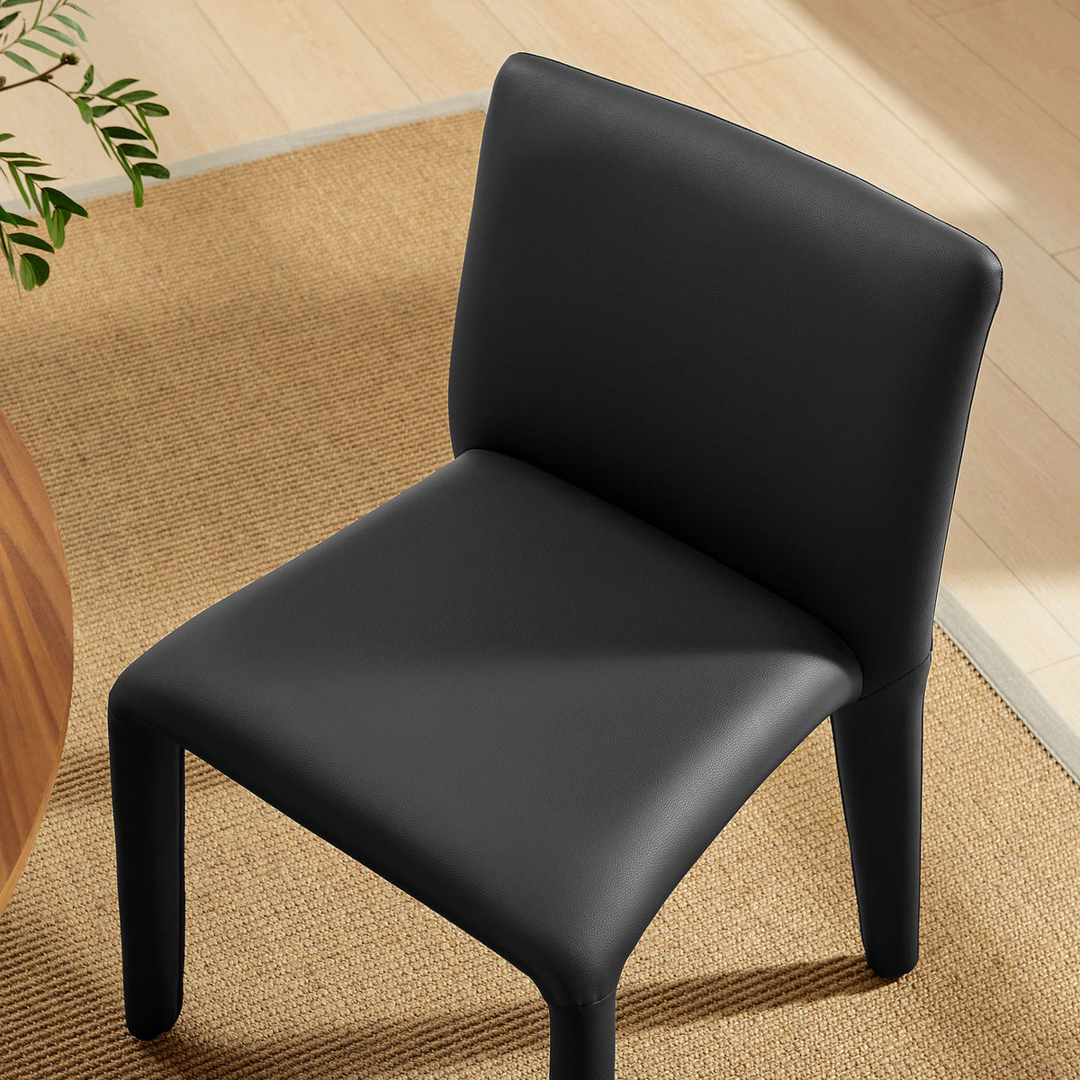 Black vegan leather dining chair styled beside a warm wood table and natural woven rug || EEI-7223-BLK || detail_room