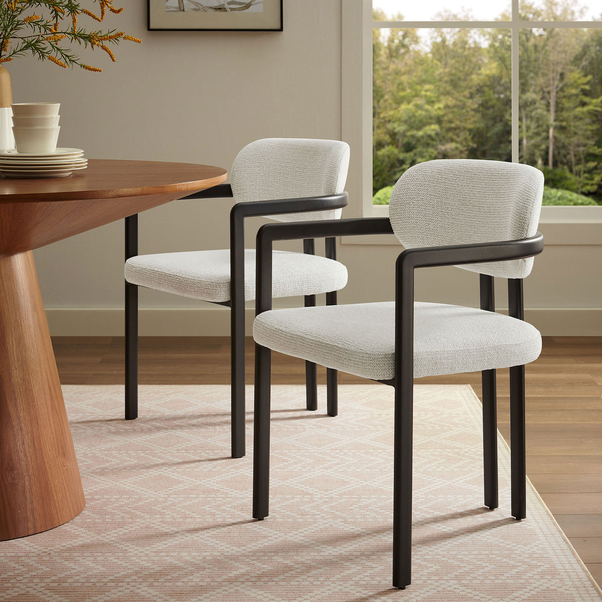 Pair of cream barrel dining chairs with black frames styled around a warm wood dining table || EEI-7229-BLK-CRE || front_angle_room