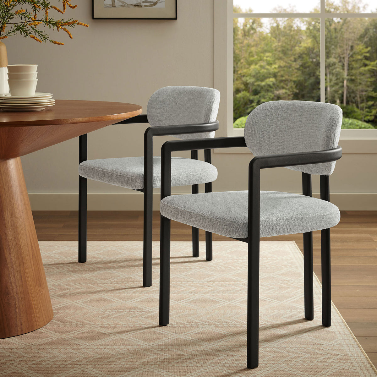 Elio gray upholstered dining chair styled beside a warm wood table in a bright windowed dining room || EEI-7229-BLK-DOV || front_angle_room