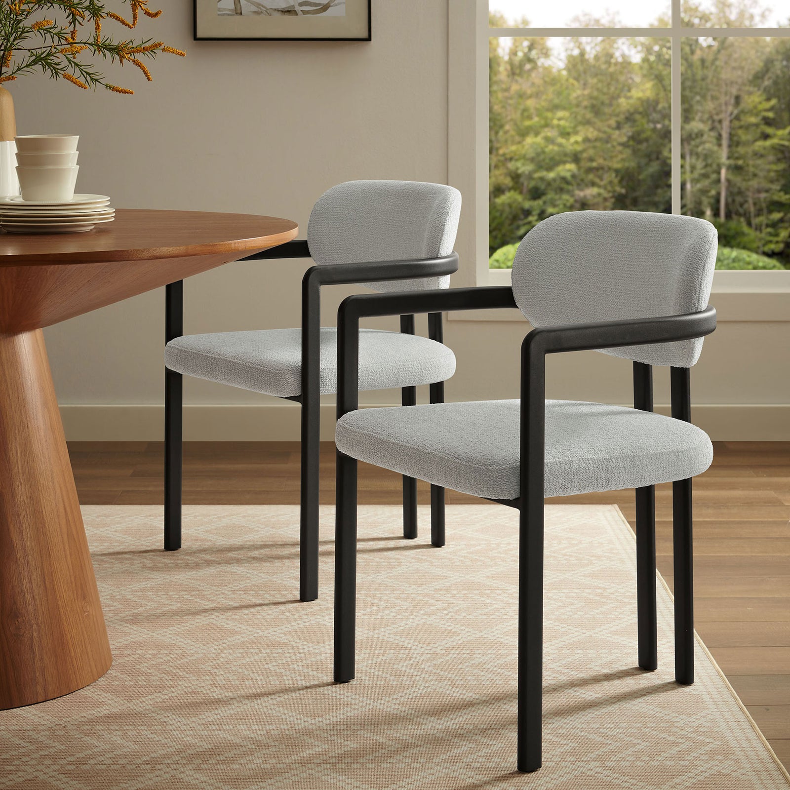 Elio gray upholstered dining chair styled beside a warm wood table in a bright windowed dining room || EEI-7229-BLK-DOV || front_angle_room