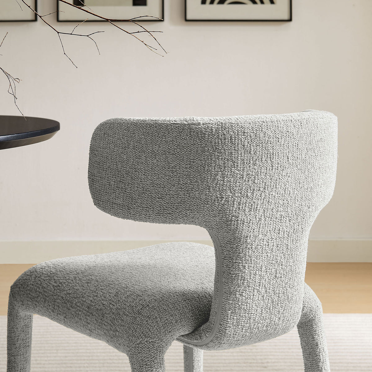 Curved dove gray boucle dining chair tucked at a round dining table in a warm contemporary dining room || EEI-7230-DOV || detail_room
