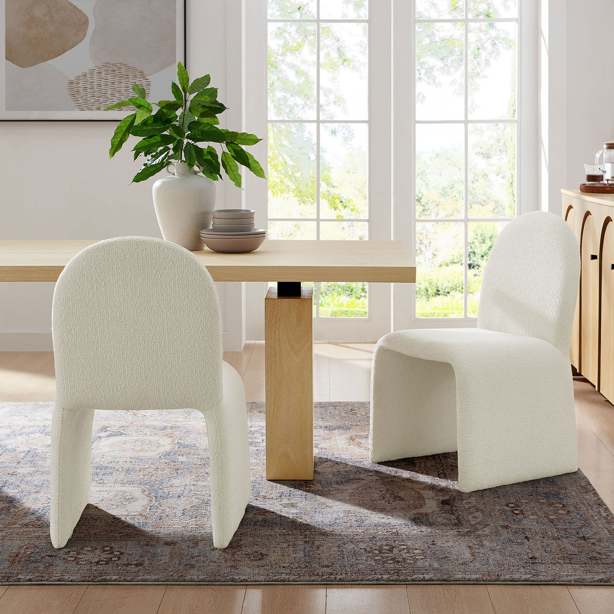 Pair of cream boucle dining chairs styled around a modern wood table in a bright dining room || EEI-7231-CRE || front_angle_room