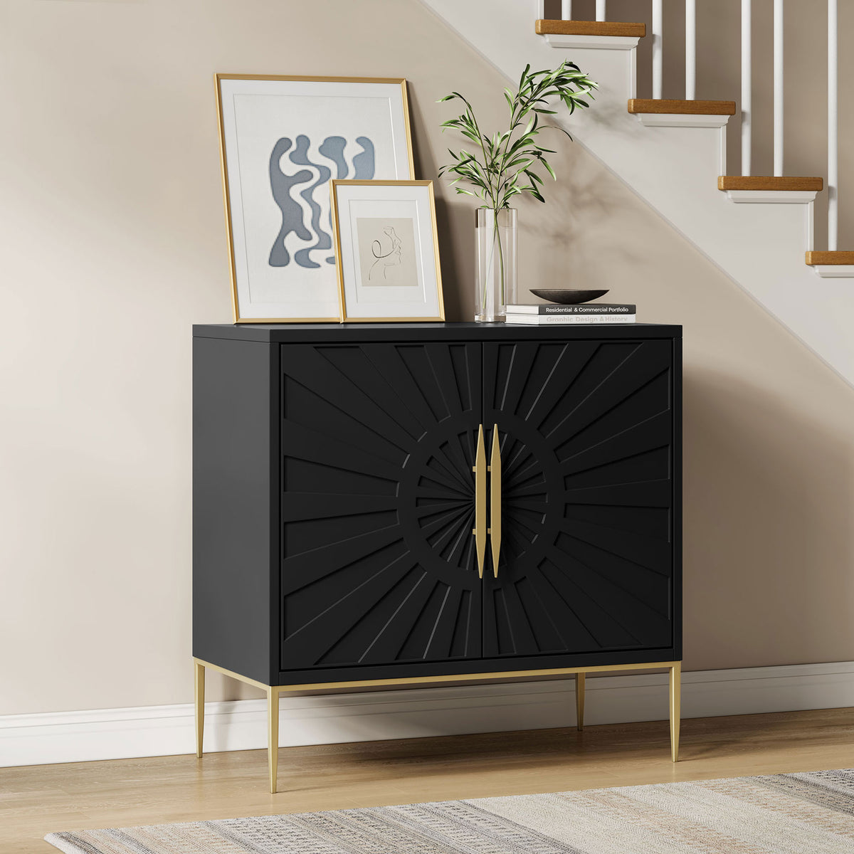 Black sunburst accent cabinet with gold base styled in an entryway with art and greenery. || EEI-7233-BLK || front_angle_room
